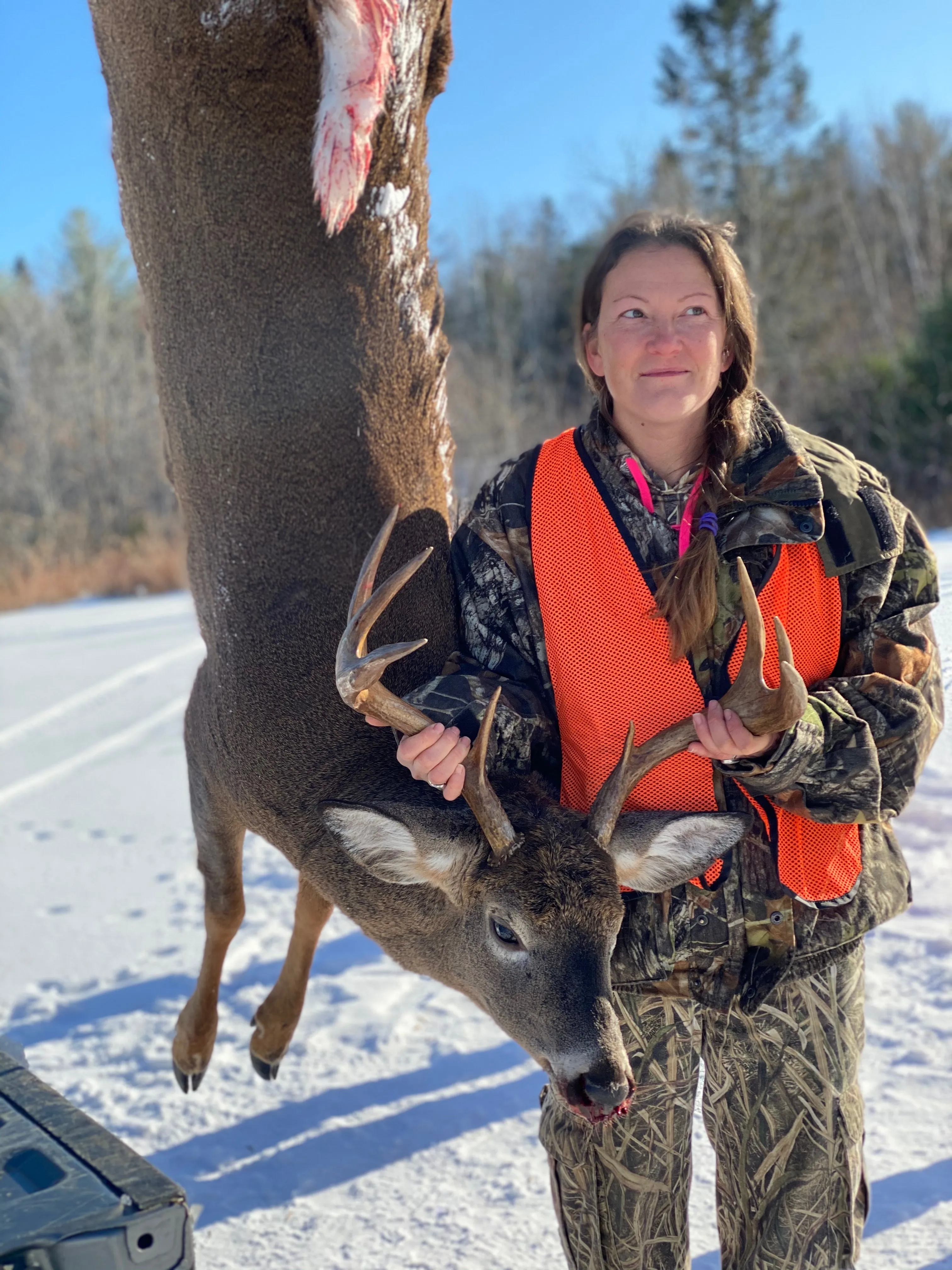 Female hunter posing wiht lagre buck deer hanging